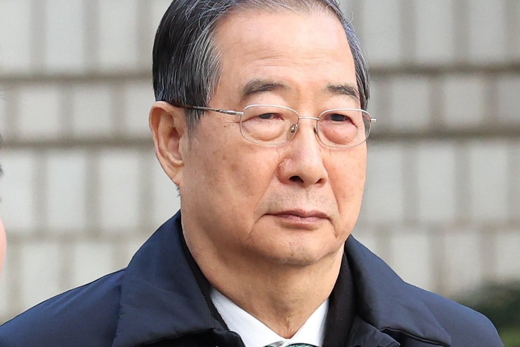 Former South Korean prime minister Han Duck-soo (right) is questioned by a reporter as he arrives at the Seoul Central District Court on Wednesday. Photo: EPA
