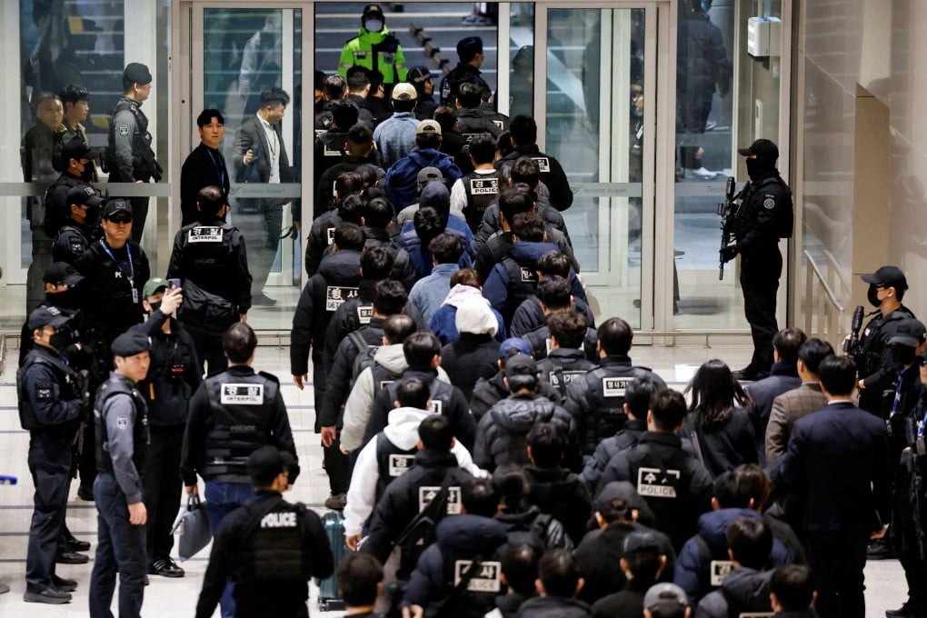 Police officers escort South Koreans allegedly involved in scam operations in Cambodia at Incheon International Airport on Friday. Photo: Reuters