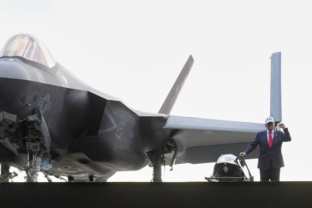 US President Donald Trump stands next to a fighter jet before speaking to members of the military on an aircraft carrier in October. Photo: AP