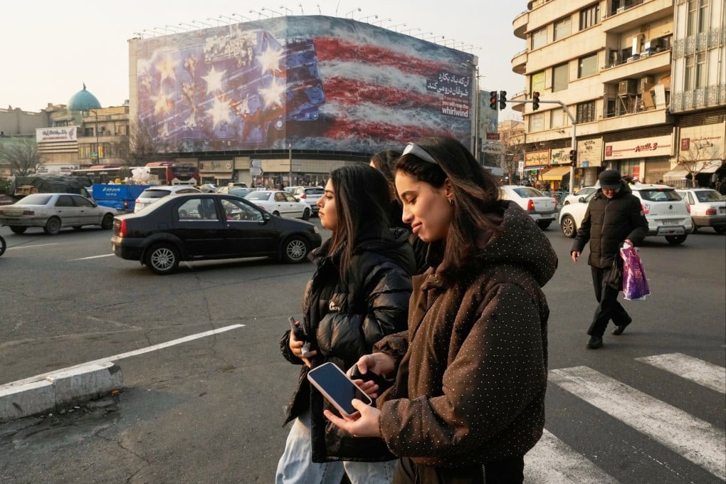 Women, not wearing the legally required headscarves, walk past the new billboard in Tehran. Photo: AP