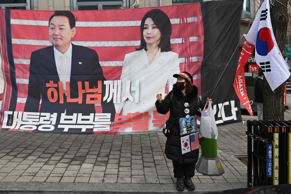 A supporter stands in front of a banner showing South Korea’s former president Yoon Suk-yeol and his wife Kim Keon-hee near the Central District Court in Seoul on January 16. Photo: AFP