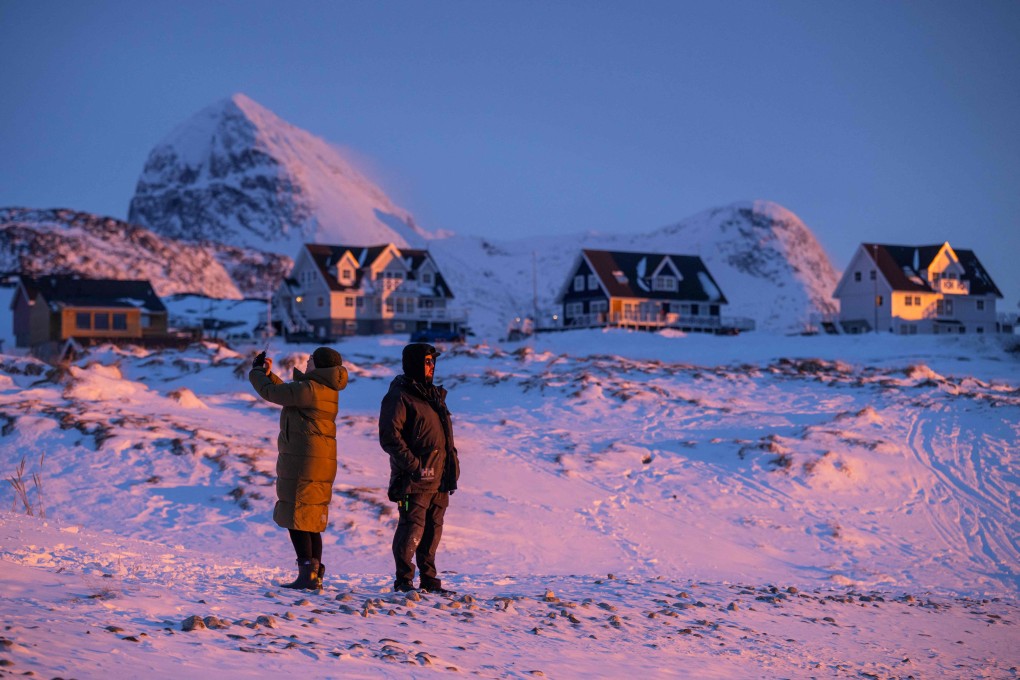 Locals stand on a snowy shoreline at dusk in Nuuk, Greenland. Greenland’s linguistic heritage reflects Inuit history and the territory’s evolving autonomy through the years. Photo: AFP