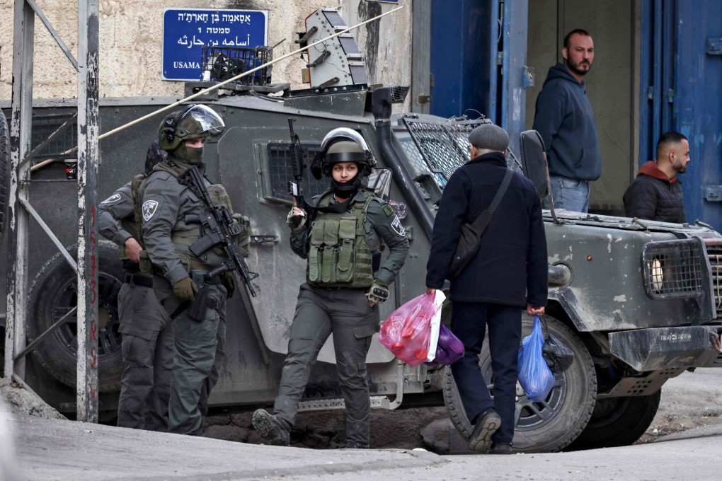 A Palestinian man carries his shopping past Israeli security forces during in Kafr Aqab in the Israeli-occupied West Bank on Wednesday. Photo: AFP