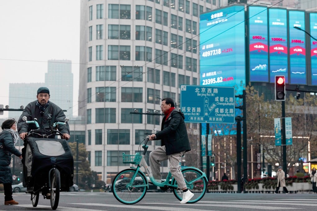 People ride bicycles below a jumbo screen displaying the latest stock exchange and economic data in Shanghai on January 6.  Photo: EPA