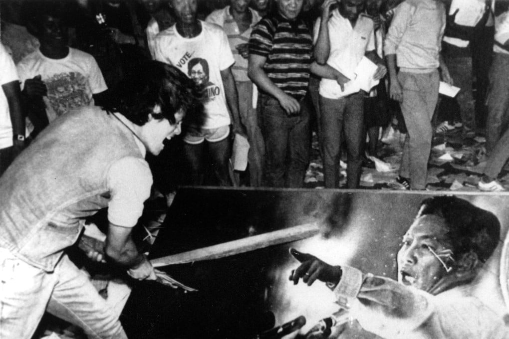 A young protester slashes an oil painting of former Philippine dictator Ferdinand Marcos as looters stormed the presidential palace in Manila following his ouster in February 1986. File photo: AP