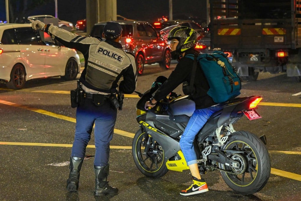 A traffic police officer guides a motorcyclist as vehicles queue to enter the Woodlands Checkpoint in Singapore. Photo: AFP
