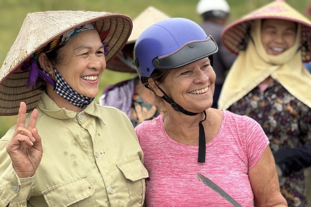 A member of an AdventureWomen tour poses for a photo with women working in rice paddies in northern Vietnam. Photo: TNS