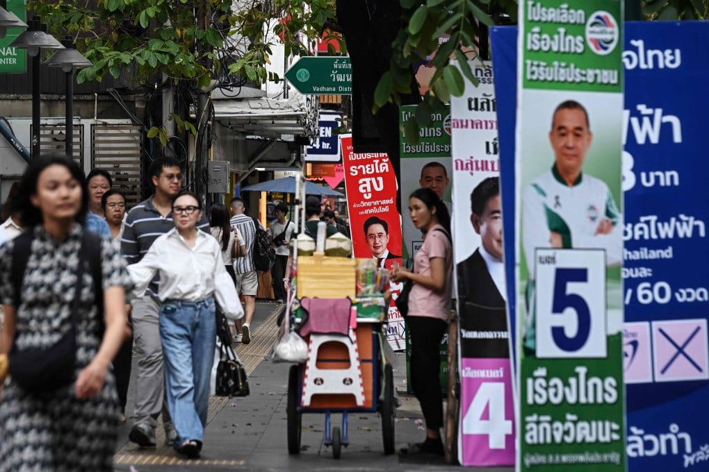 Pedestrians walk past campaign posters in Bangkok on Tuesday ahead of Thailand’s general election. Photo: AFP