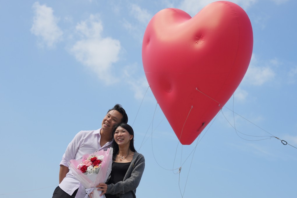 A couple stand in front of the “Chubby Hearts Hong Kong” art installation by Anya Hindmarch in Kennedy Town, Hong Kong, on Valentine’s Day in 2024. Photo: Eugene Lee