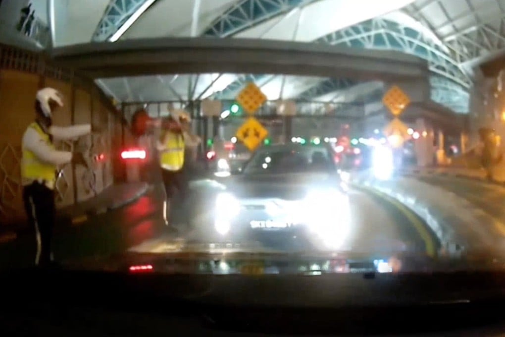 Malaysian police face off with a Singapore-registered car driving against the flow of traffic at the Sultan Iskandar Building immigration complex. The incident occurred last month. Photo: Handout