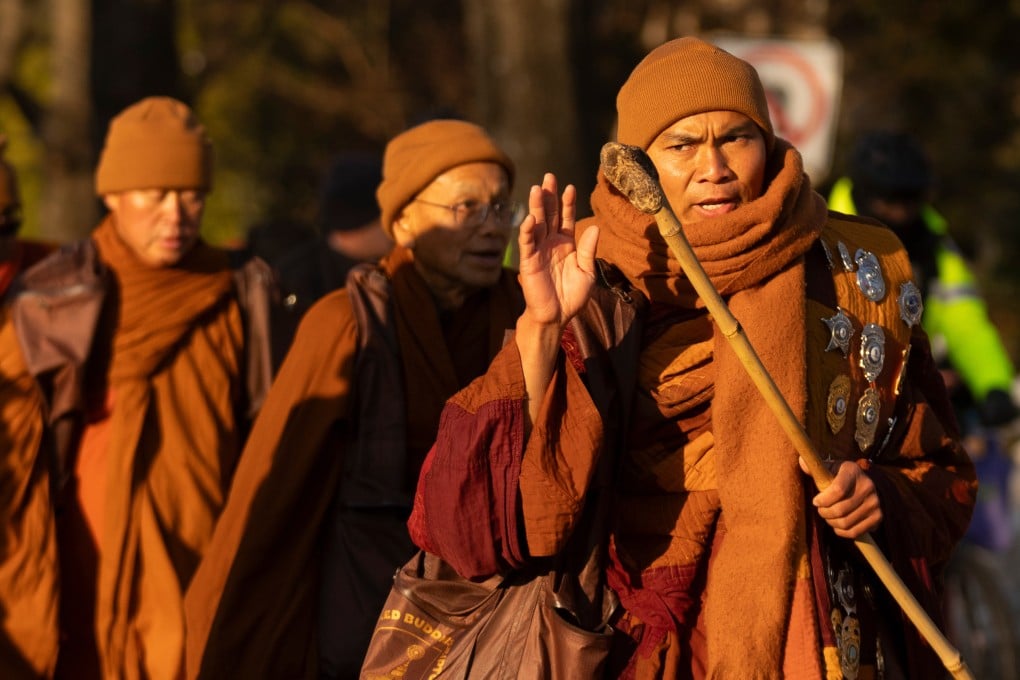 Monk Bhikkhu Pannakara waves as marchers in the Walk For Peace pass through Washington on Tuesday. Photo: AP