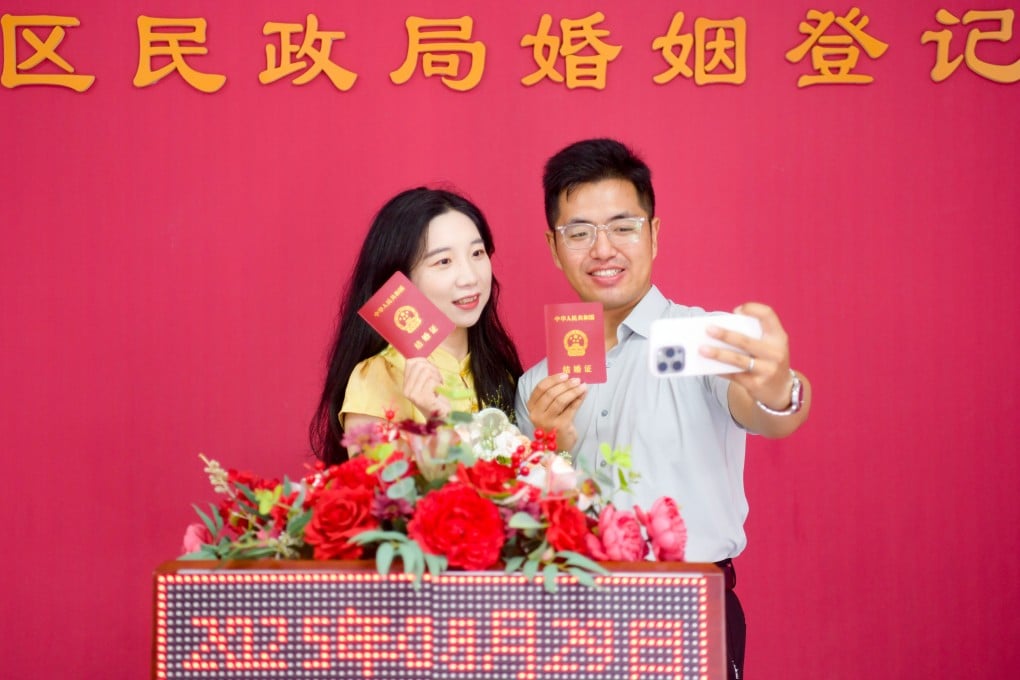 Newlyweds take a selfie with their marriage certificates in August at the marriage registration office in China’s Henan province. Photo: Getty Images