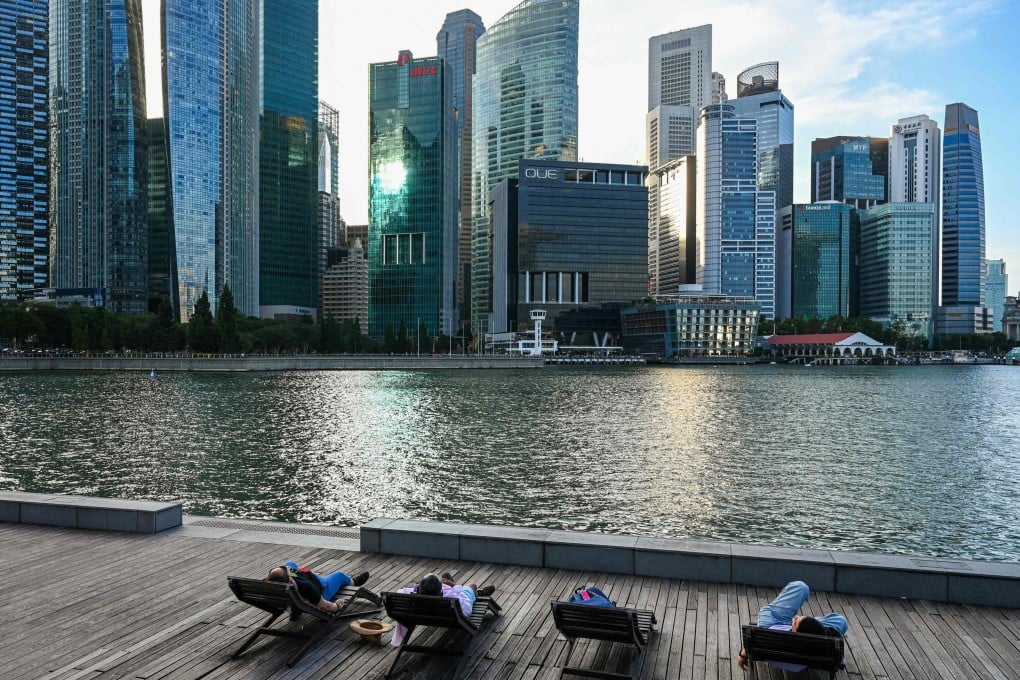 People relax on beach chairs along the boardwalk during sunset at Marina Bay in Singapore on February 9. Photo: AFP
