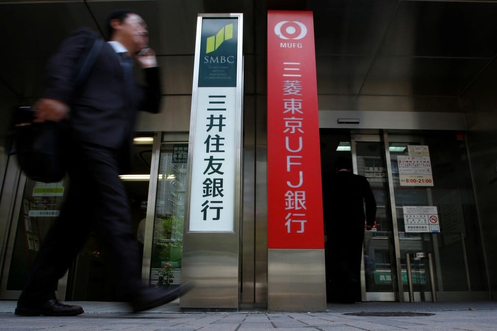 A man walks past ATM booths for Japan’s mega banks, Sumitomo Mitsui Banking Corporation, left, and Bank of Tokyo-Mitsubishi UFJ, in Tokyo, on February 6. Photo: Reuters