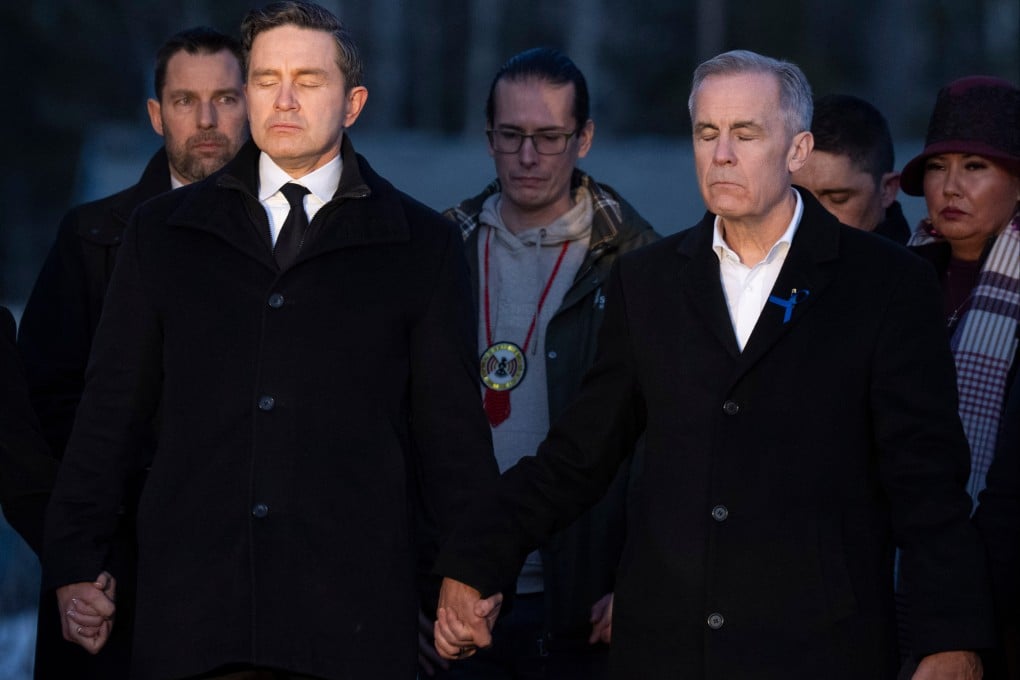 Prime Minister Mark Carney, right, and Conservative Leader Pierre Poilievre join hands while attending a vigil for the victims of a mass shooting, in Tumbler Ridge, BC, on Friday. Photo: AP