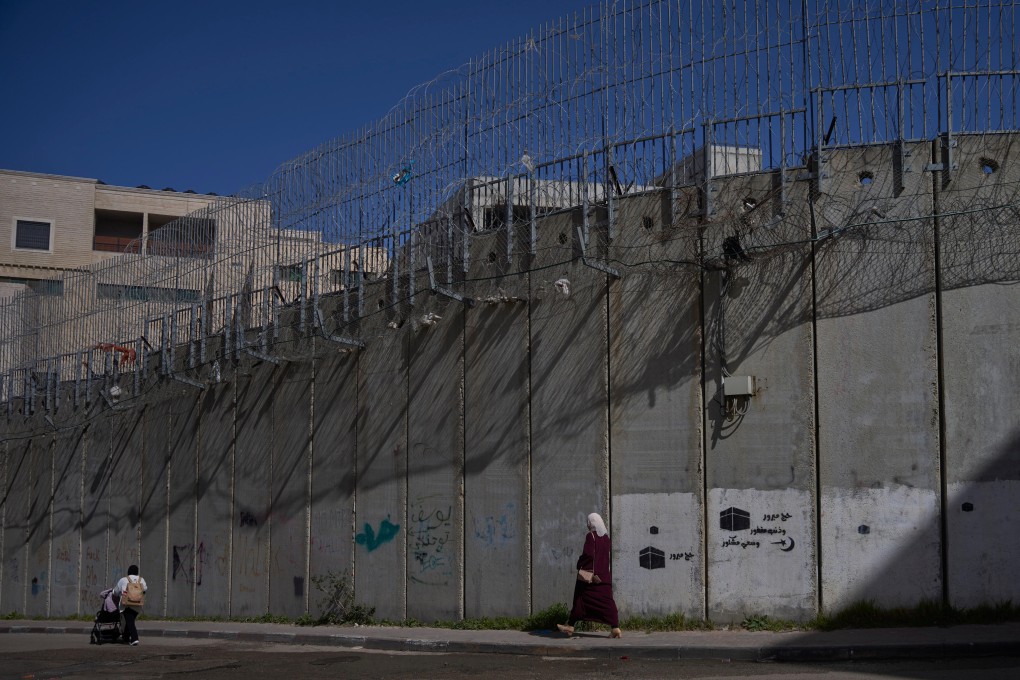 Palestinians walk along the separation barrier between the West Bank and east Jerusalem neighbourhood of Beit Hanina. Photo: AP