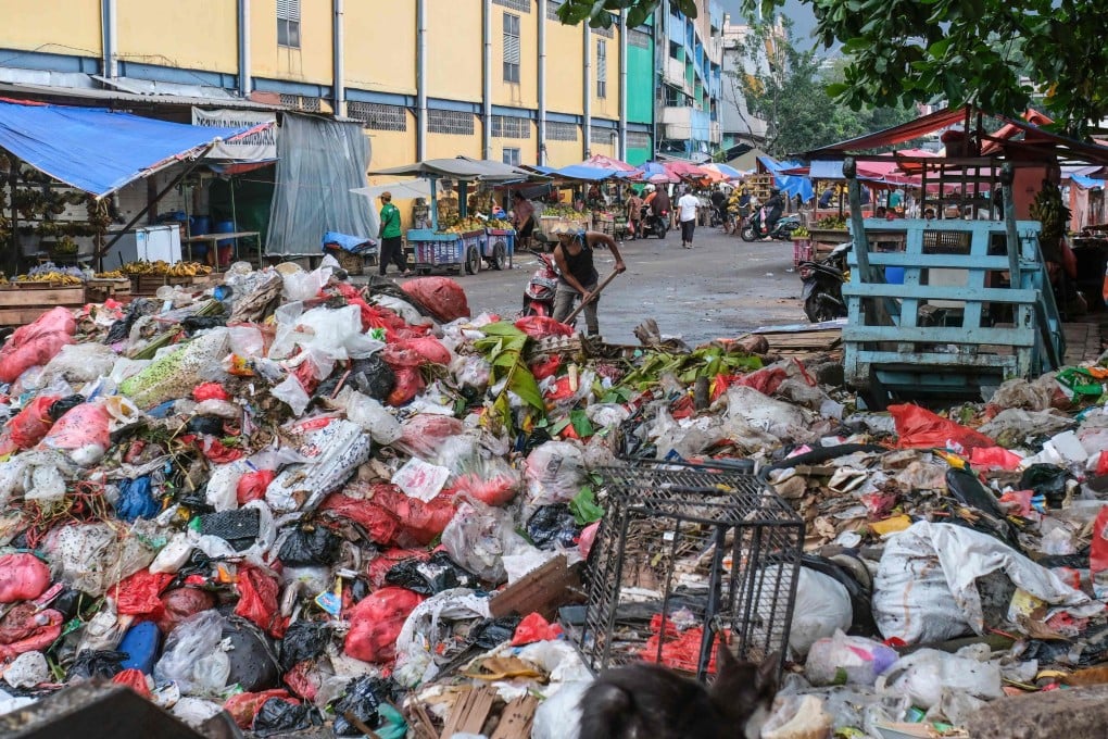 A man uses a shovel on a pile of rubbish on a public road in Pasar Minggu, Jakarta. Photo: AFP