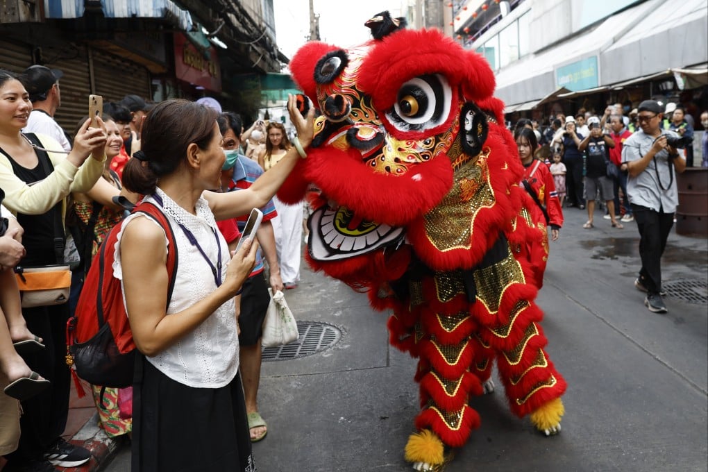 A tourist interacts with a lion dance performer in Bangkok’s Chinatown, Thailand, on Monday. Photo: EPA