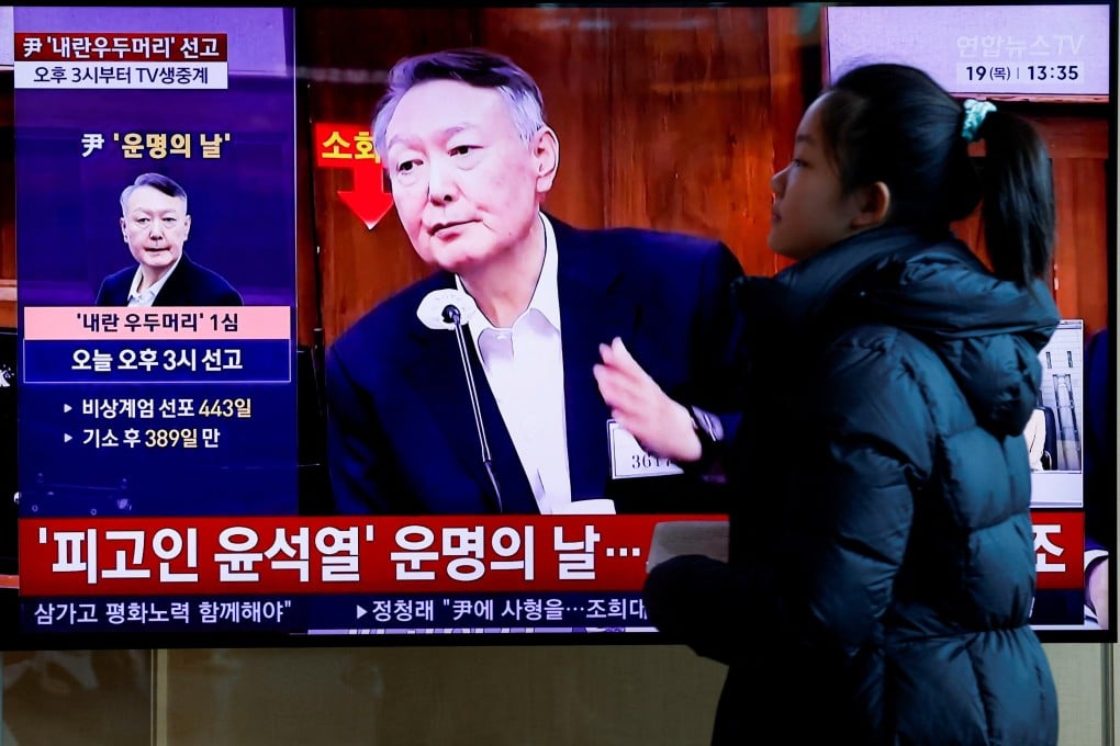 A woman walks past a television screen in Seoul broadcasting a news report on Yoon Suk-yeol’s sentencing on Thursday. Photo: Reuters
