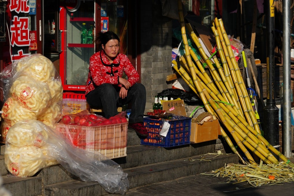A vendor sits at the doorway to her store in Beijing on February 18. China’s leadership is pivoting towards people-centric, consumption-led economic growth. Photo: Getty Images