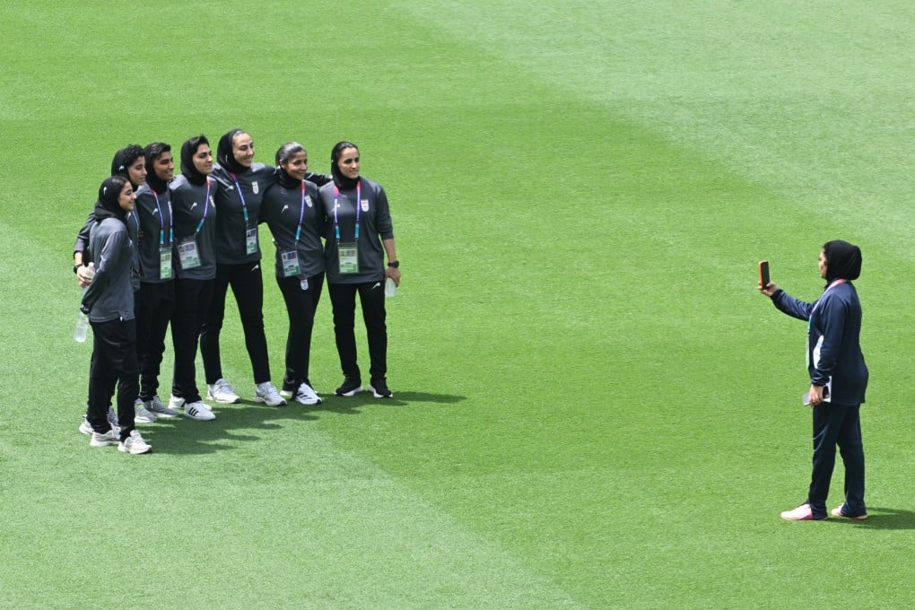 Members of the Iranian women’s team pose for photographs after inspecting the pitch ahead of their game against South Korea at Robina Stadium on the Gold Coast. Photo: AP