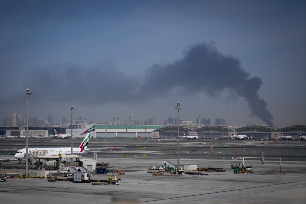 A plume of smoke from an Iranian strike rises behind planes parked at Dubai International Airport on Sunday, March 1. Photo: AP
