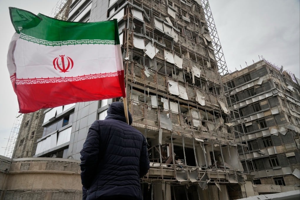 A man with an Iranian flag surveys the damaged facade of Gandhi Hospital, which was hit on Sunday during the US-Israel strikes. Photo: AP