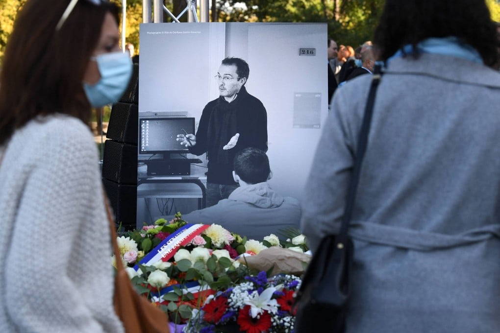 Members of the public stand in front of a photograph of Samuel Paty as they attend a memorial in Eragny-sur-Oise, northwestern Paris, France in October 2021, a year after the teacher was beheaded. Photo: AFP