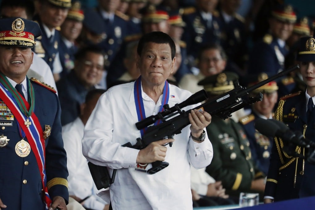 Philippine President Rodrigo Duterte (centre) holds a Galil sniper rifle during the national police chief change of command ceremony inside Camp Crame in Quezon City in April 2018. Duterte is accused of overseeing a campaign of extrajudicial killings linked to his signature “war on drugs”. Photo: EPA-EFE