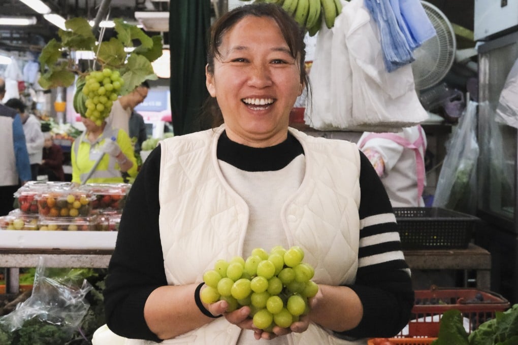 Organic farmer Yan Fuqin holds a bunch of her farm’s shine muscat grapes at her stall at Hong Kong’s Tsuen Wan Market. Photo: Hei Kiu Au