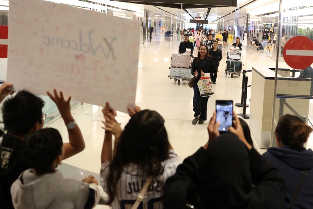 Family members cheer as passengers return to Singapore from the Middle East at Changi Airport on Thursday. Photo: Reuters