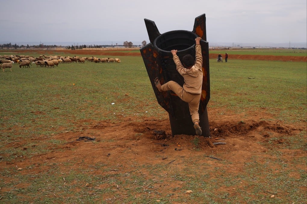 Exposing himself to the danger of unexploded ordnance, a boy tries to climb on an Iranian projectile that landed in an open field in the outskirts of Qamishli, eastern Syria. Photo: AP