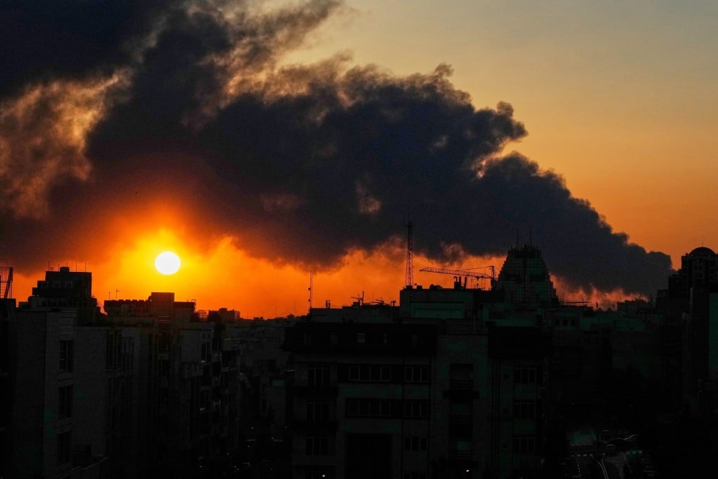 The sun sets behind a plume of smoke from a US-Israeli military strike in Tehran, Iran, on Tuesday. Photo: AP
