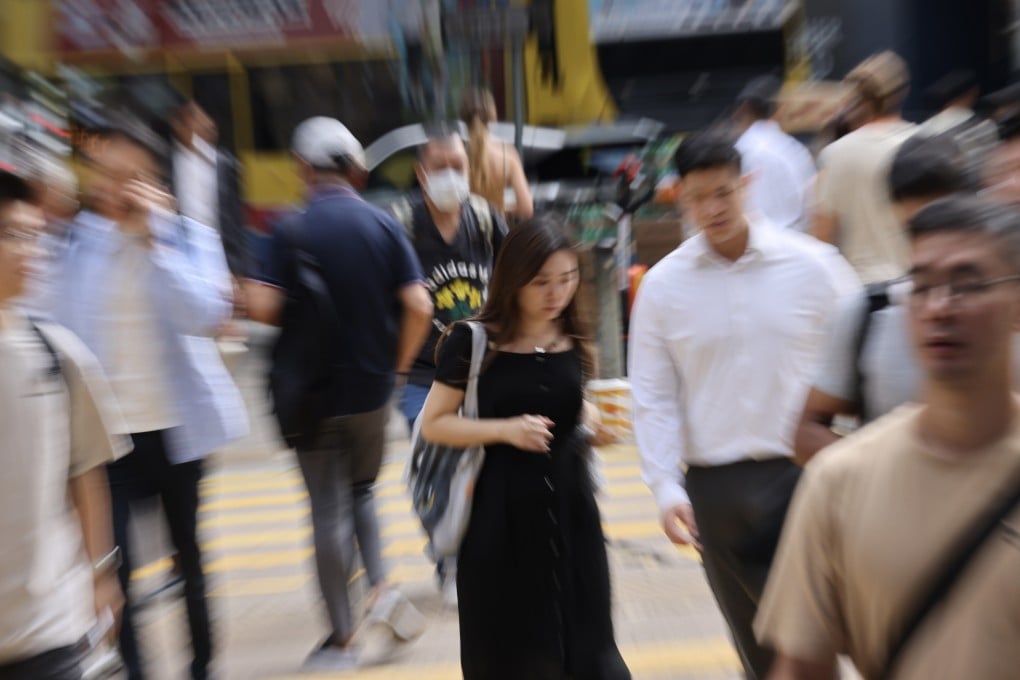 People cross a road in Central district in 2025. As society embraces AI, we need to ensure its development and adoption in business do not come at the expense of Hong Kong’s mental wellness. Photo: Karma Lo