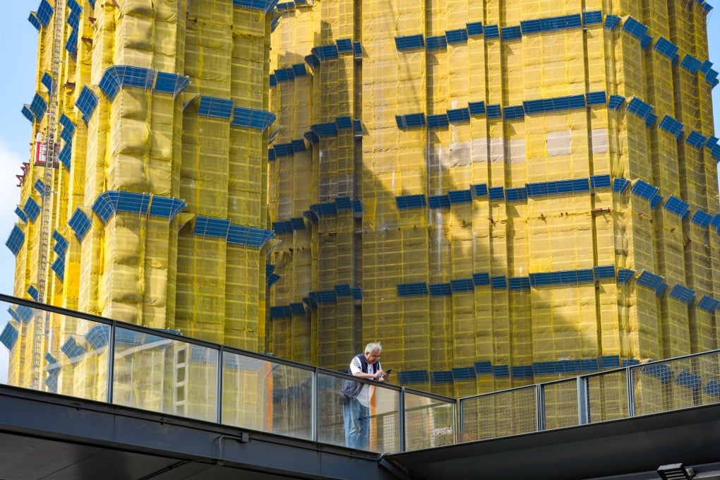 A man looks at his mobile phone in Kai Tak in front of a residential building under construction. Photo: Jelly Tse