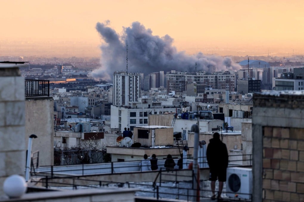 A person stands on the roof of a building looking at a plume of smoke rising after a strike on Tehran on Tuesday. The escalating conflict in the Middle East is leading to tight supplies of sulphur in China. Photo: AFP