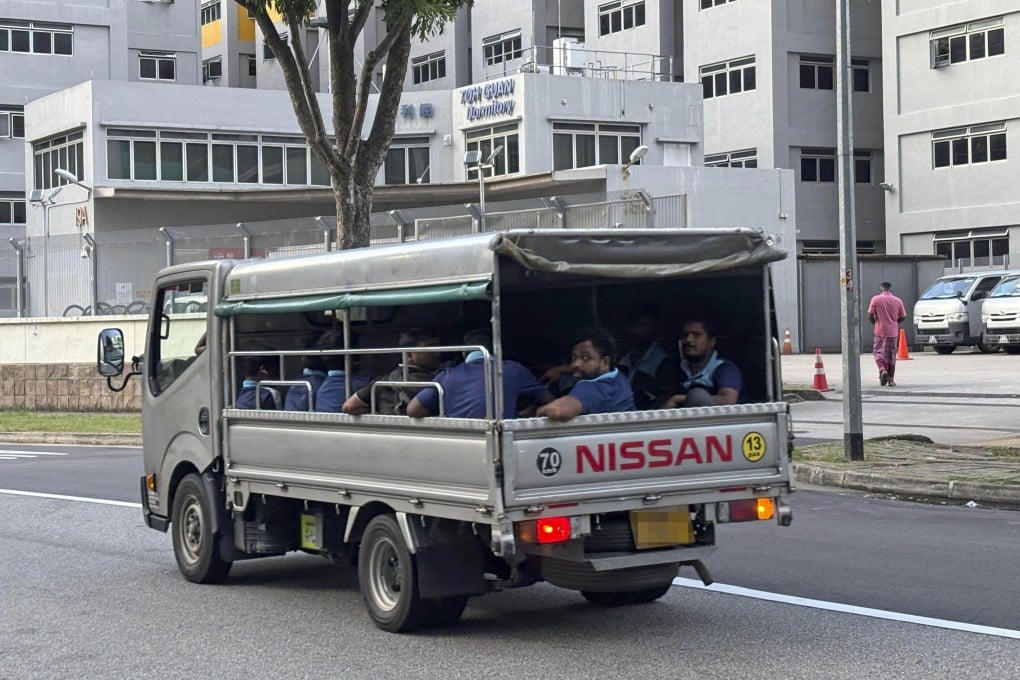 Migrant workers ride in the back of an open lorry in Singapore on Dec 6, 2025. The government is moving to ban the use of caged lorries to transport workers as part of efforts to improve transport safety. Photo: Kyodo
