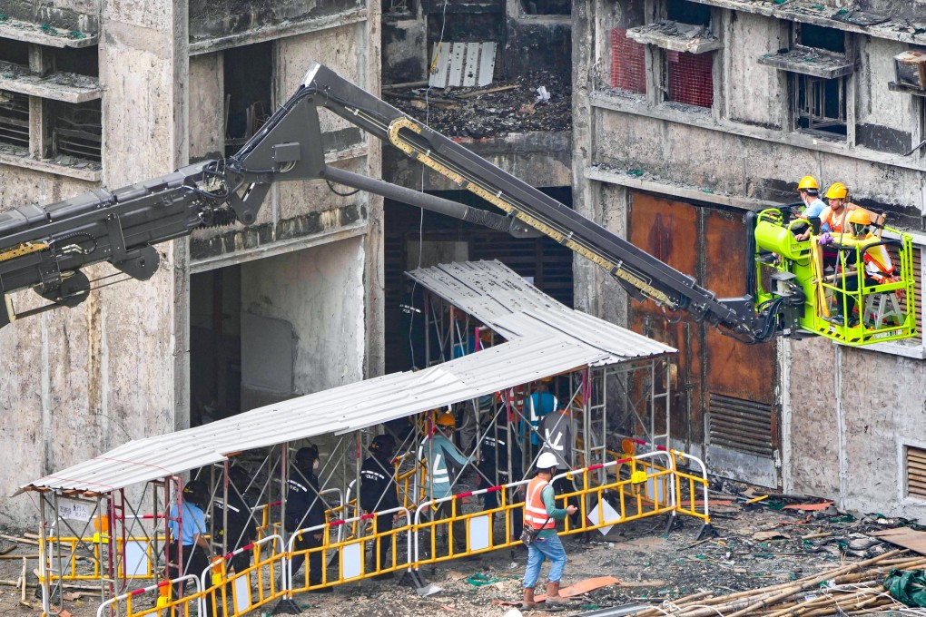 Construction workers at Wang Fuk Court are escorted by police officers as part of enhanced security screening. Photo: Sam Tsang