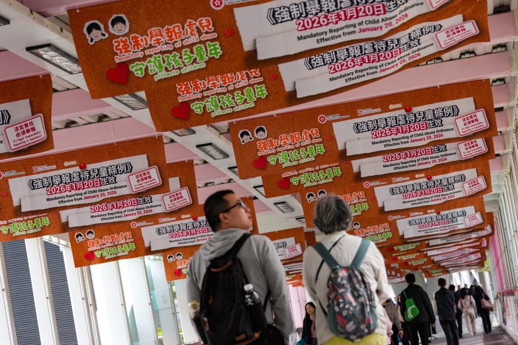 People walk across a footbridge in Admiralty covered with posters promoting the Mandatory Reporting of Child Abuse Ordinance on January 20. Photo: Jelly Tse