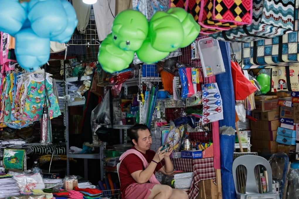 A shopkeeper looks at his smartphone while waiting customers in Manila. The Philippines’ budget deficit hit a record high last year. Photo: EPA