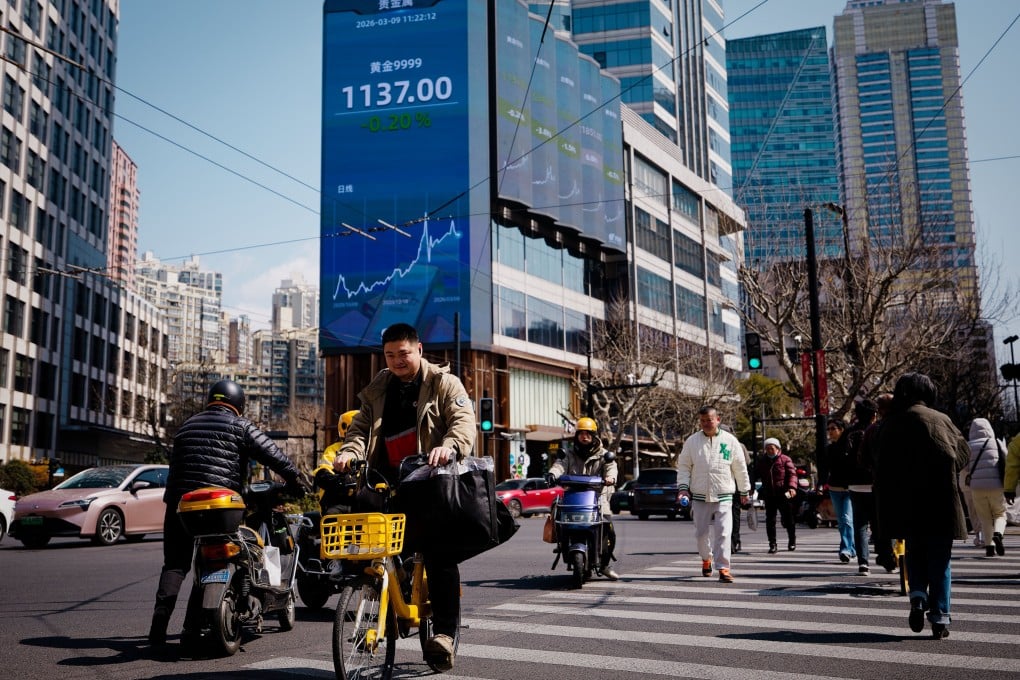 People cross the street beneath a screen showing stock exchange data in Shanghai on March 9, 2026. Photo: EPA