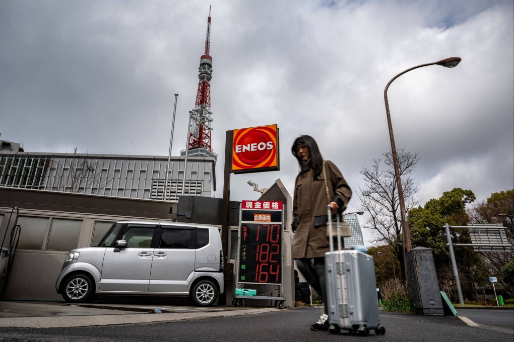 A woman walks past a petrol station in Tokyo. Photo: AFP
