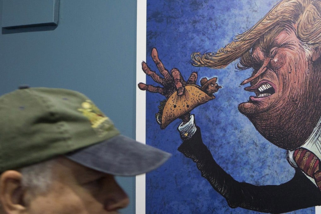 A visitor walks past a cartoon of Donald Trump holding a man wrapped in a taco at an exhibition at the Caricature Museum in Mexico City in November 2016. Photo: AP