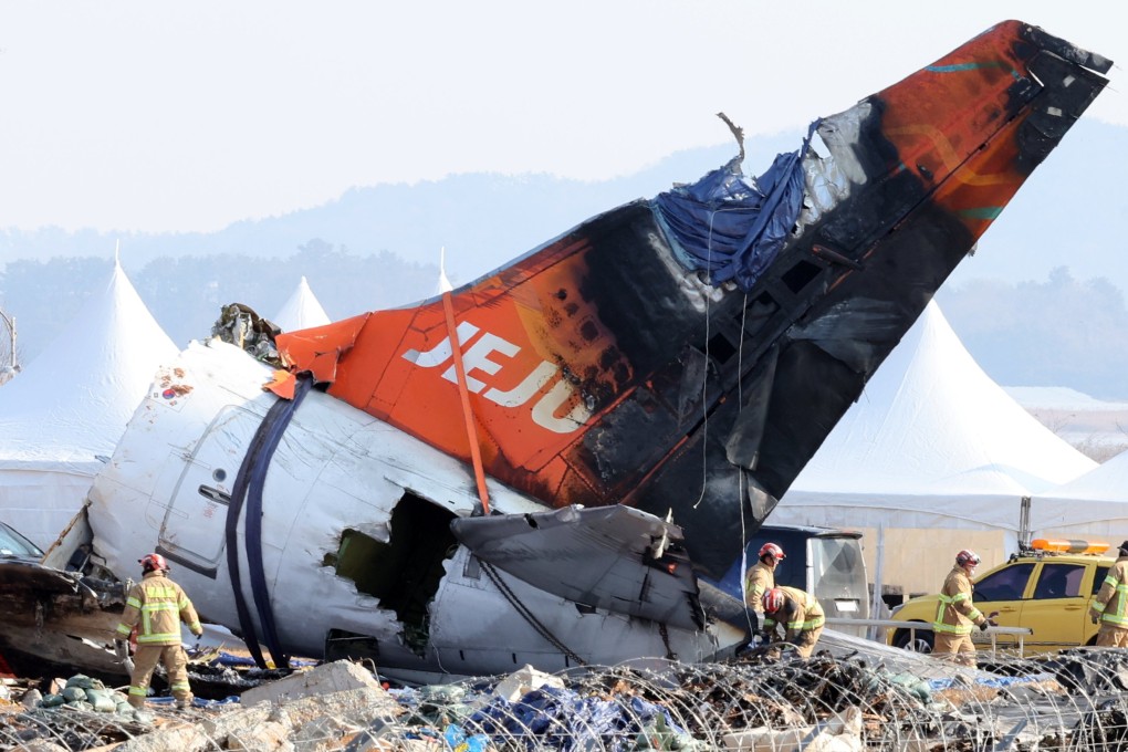 Firefighters remove tarpaulin sheets covering the debris of a Jeju Air plane following its crash on December 29, 2024.  Photo: Yonhap/EPA-EFE