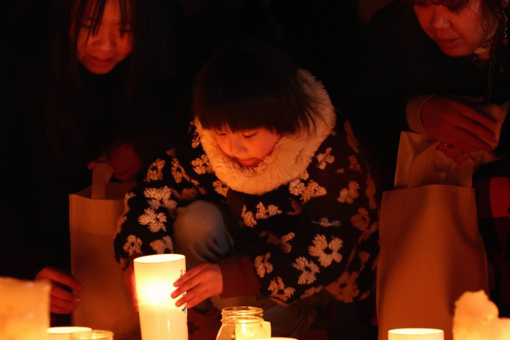 People offer prayers and light candles during a memorial in front of Futaba Station on Tuesday ahead of the 15th anniversary of the Fukushima earthquake and tsunami.  Photo: Jiji Press/EPA