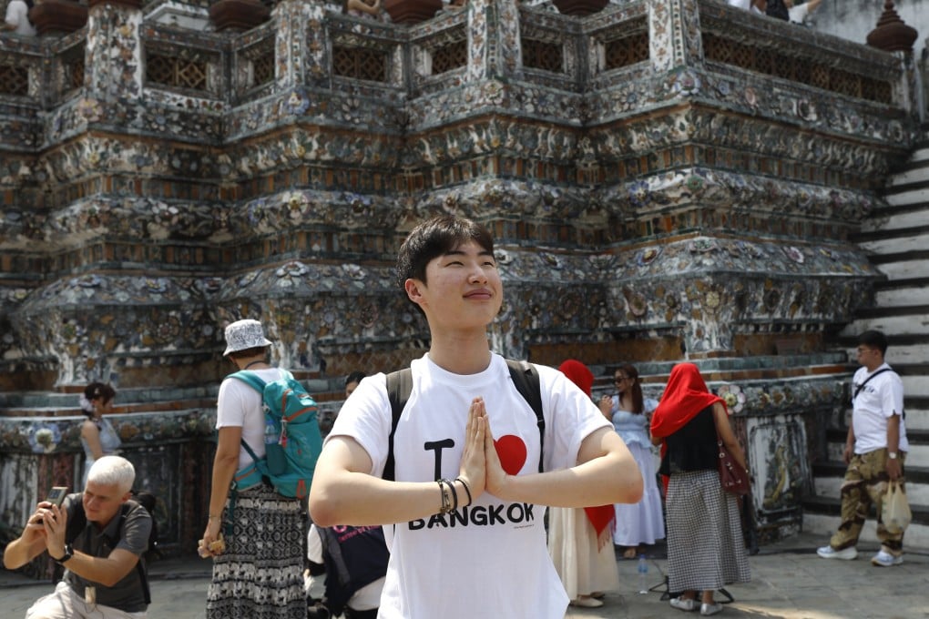 A tourist poses for a photo doing the traditional Thai greeting during his visit to the Temple of Dawn in Bangkok on January 19. Photo: EPA