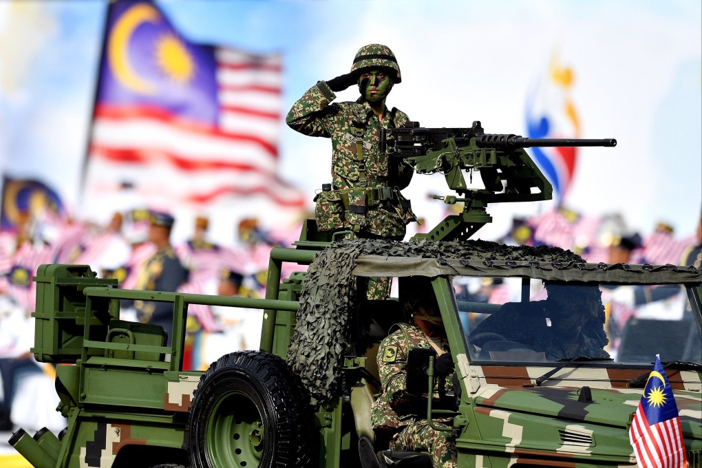A Malaysian soldier salutes from an armoured vehicle during a National Day parade in Putrajaya, Malaysia, in 2018. Photo: AFP