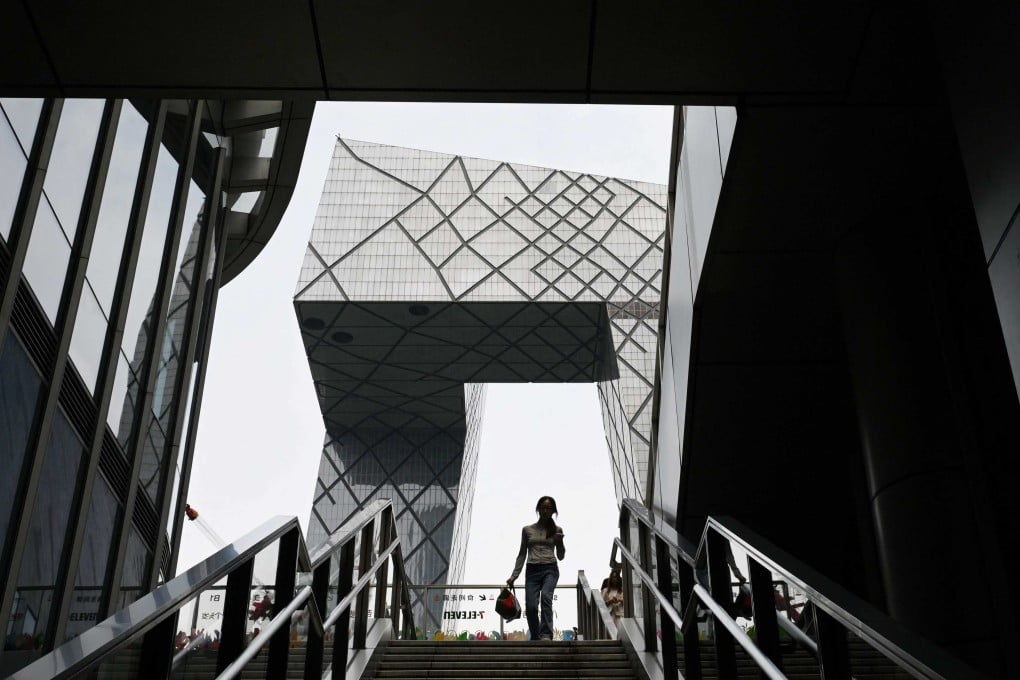 A woman walks down a staircase next to the China Central Television (CCTV) headquarters building in Beijing on July 31, 2025. Photo: AFP