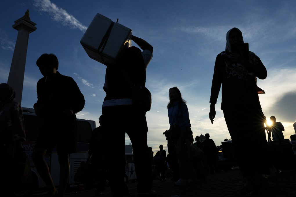 People carry their belongings as they arrive for a free bus trip to their hometowns organised by the Jakarta provincial government in Jakarta, Indonesia, on Tuesday. Photo: AP