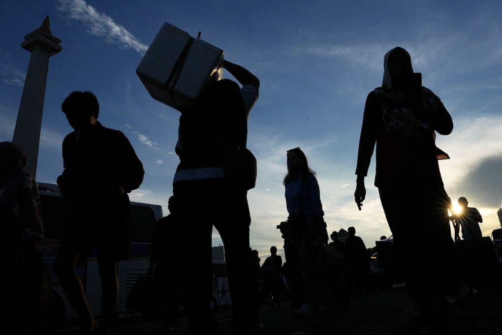 People carry their belongings as they arrive for a free bus trip to their hometowns organised by the Jakarta provincial government in Jakarta, Indonesia, on Tuesday. Photo: AP
